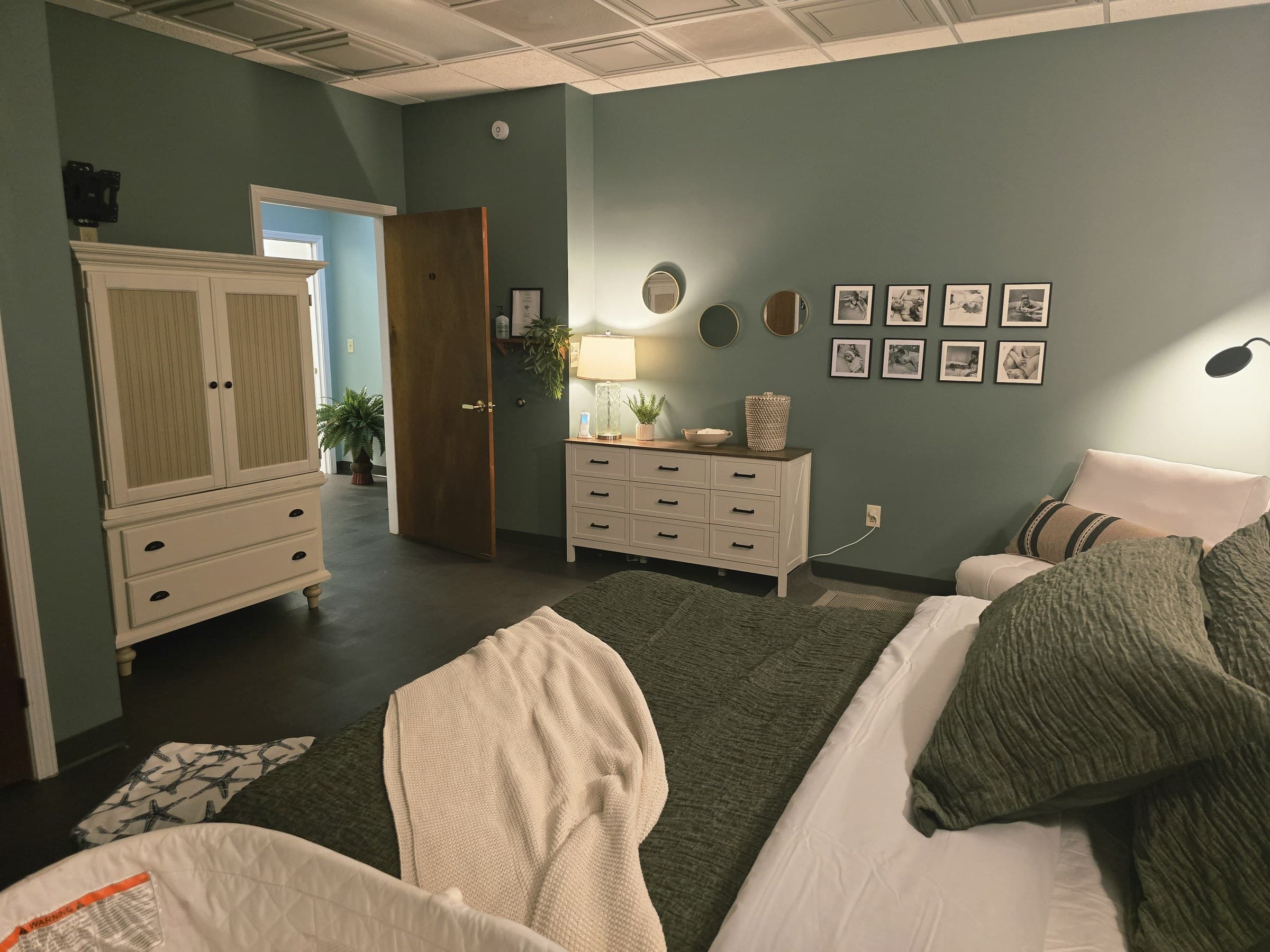A private birth suite at Transitions Birth Center — sage green walls, warm lighting, and a comfortable bed